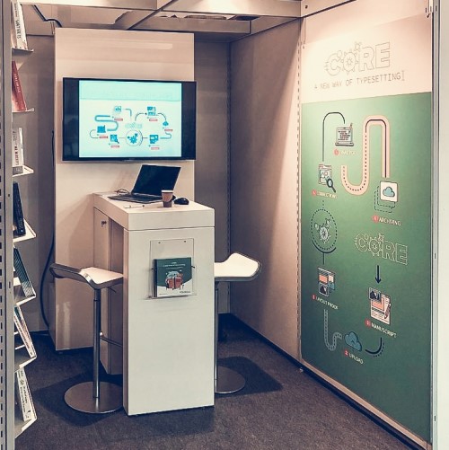 Beursstand met schermpresentatie en grafische banners over uitgeverijsoftware en redactionele tools.