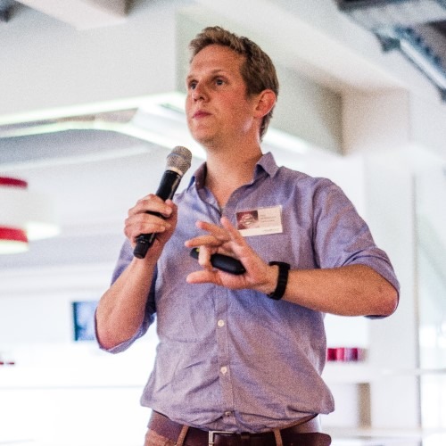 Man geeft presentatie met microfoon in een moderne vergaderruimte.