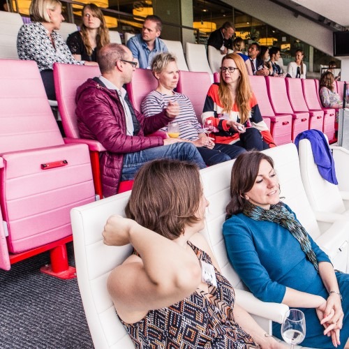 Mensen in een tribune praten en ontspannen tijdens een bijeenkomst of evenement met redactionele focus.