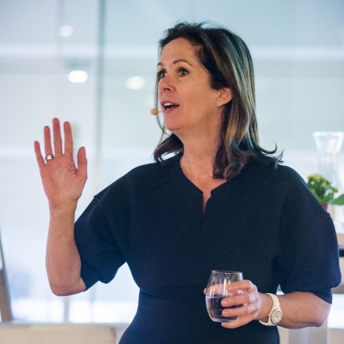Woman giving a presentation while holding a glass.