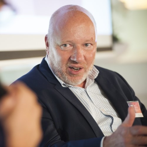 Man in gesprek tijdens een zakelijke bijeenkomst, draagt een pak.