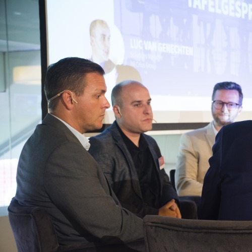 Mensen in pak tijdens een conferentie presentatie, zittend in een paneldiscussie.