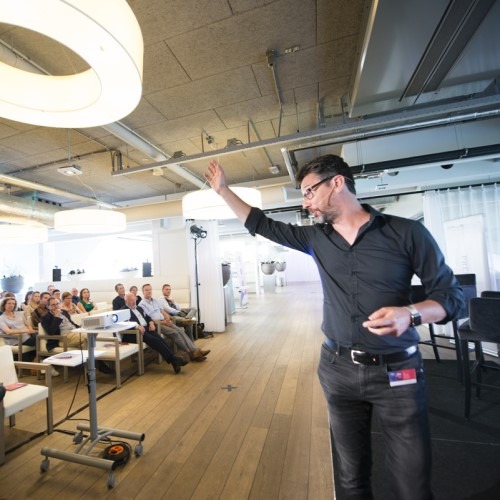 Man giving a presentation to an audience in a modern, bright conference room.