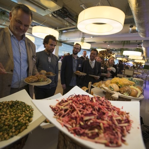 Mensen bij een buffet met verschillende gerechten in een moderne ruimte.