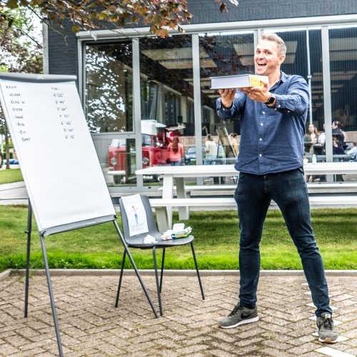 Man presenteert buiten met whiteboard en stoel.