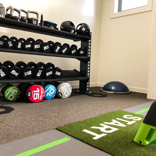 Fitnessruimte met halters, gewichten en een startlijn op de vloer.