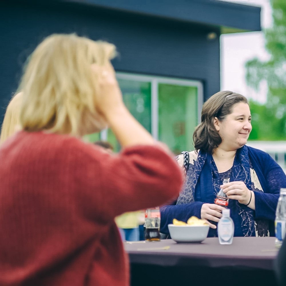 Mensen praten en drinken buiten aan een tafel tijdens een informeel samenzijn.