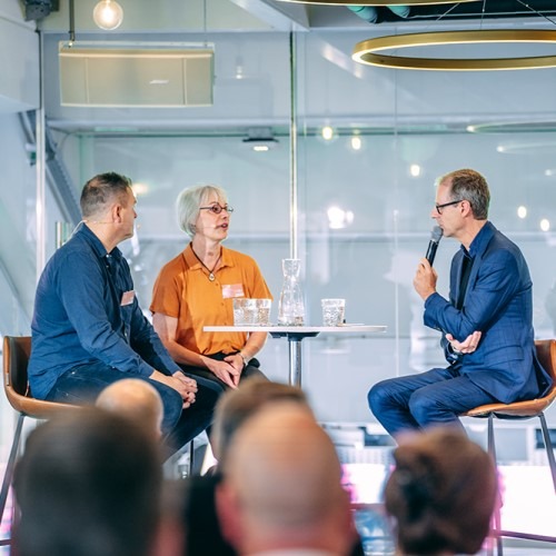 Three people engaged in a panel discussion on stage about publishing and production processes.