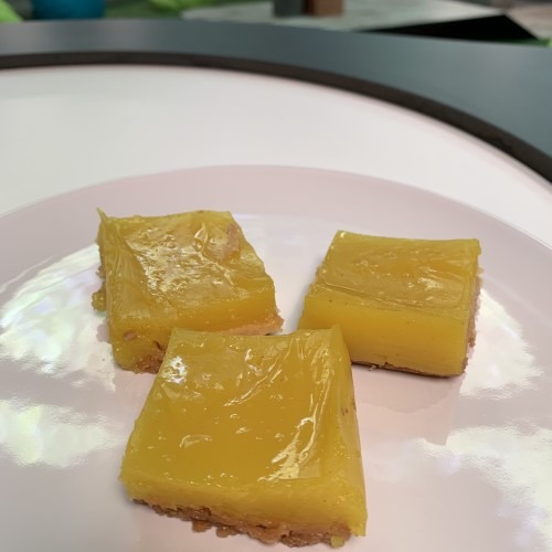 Drie gele dessertblokjes op een bord, glanzend en rechthoekig gepresenteerd.