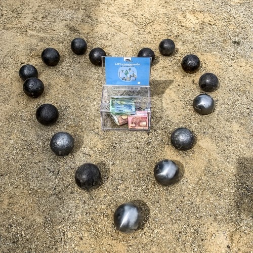 Petanqueballen in een hartvorm op zand met een verpakking in het midden.