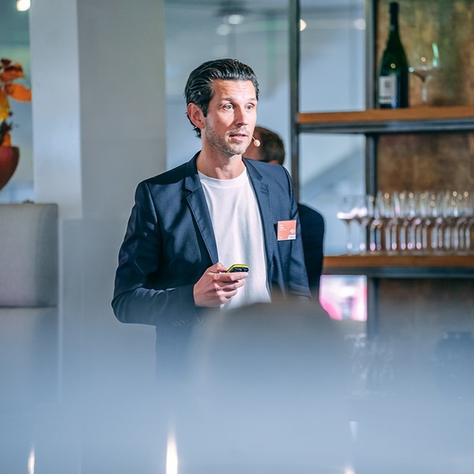 Man in a suit giving a presentation in a modern space.