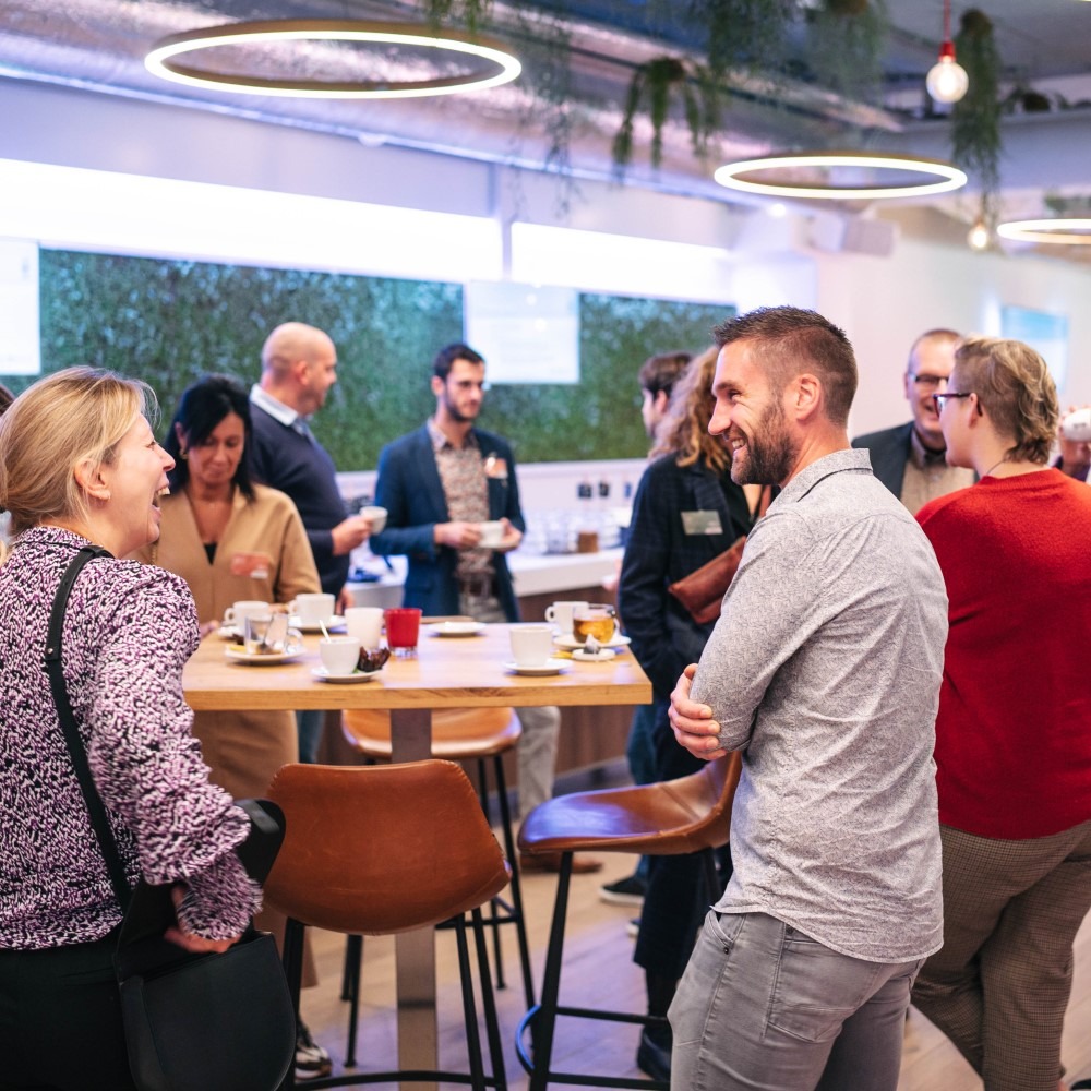 Mensen netwerken in een moderne kantoorruimte met planten en stoelen.