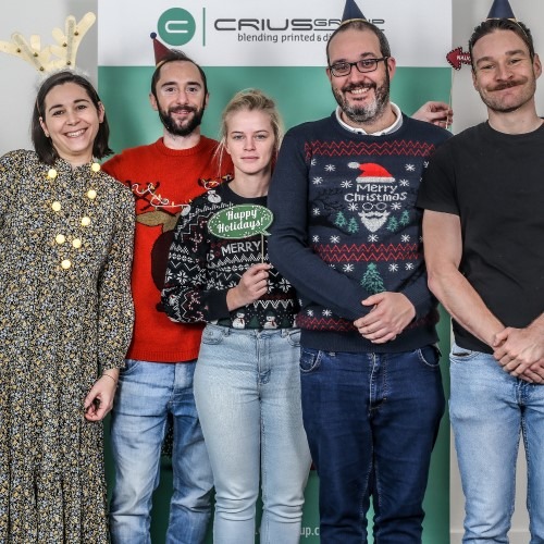 Vijf mensen poseren voor een Crius Group-banner tijdens een feestelijke gelegenheid.