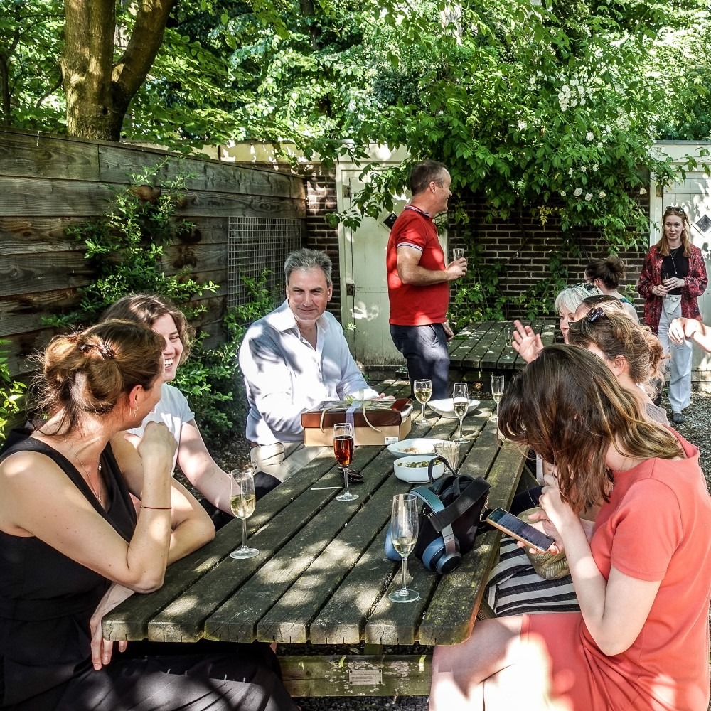 Group of people sitting at an outdoor table, conversing and enjoying the weather.