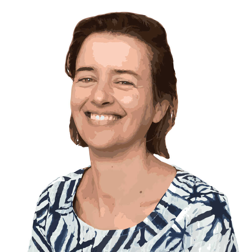 Woman smiling at the camera, wearing a summer dress with blue patterns.