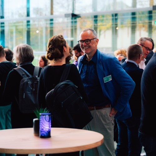 Group of people conversing at a networking event in a modern office with large windows.