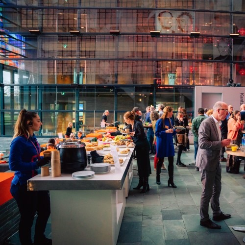 People at a buffet during a networking event in a modern space with glass and lighting.