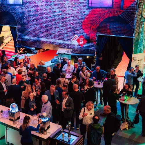 Group of people at an event in a colorful space, networking and socializing at tables.